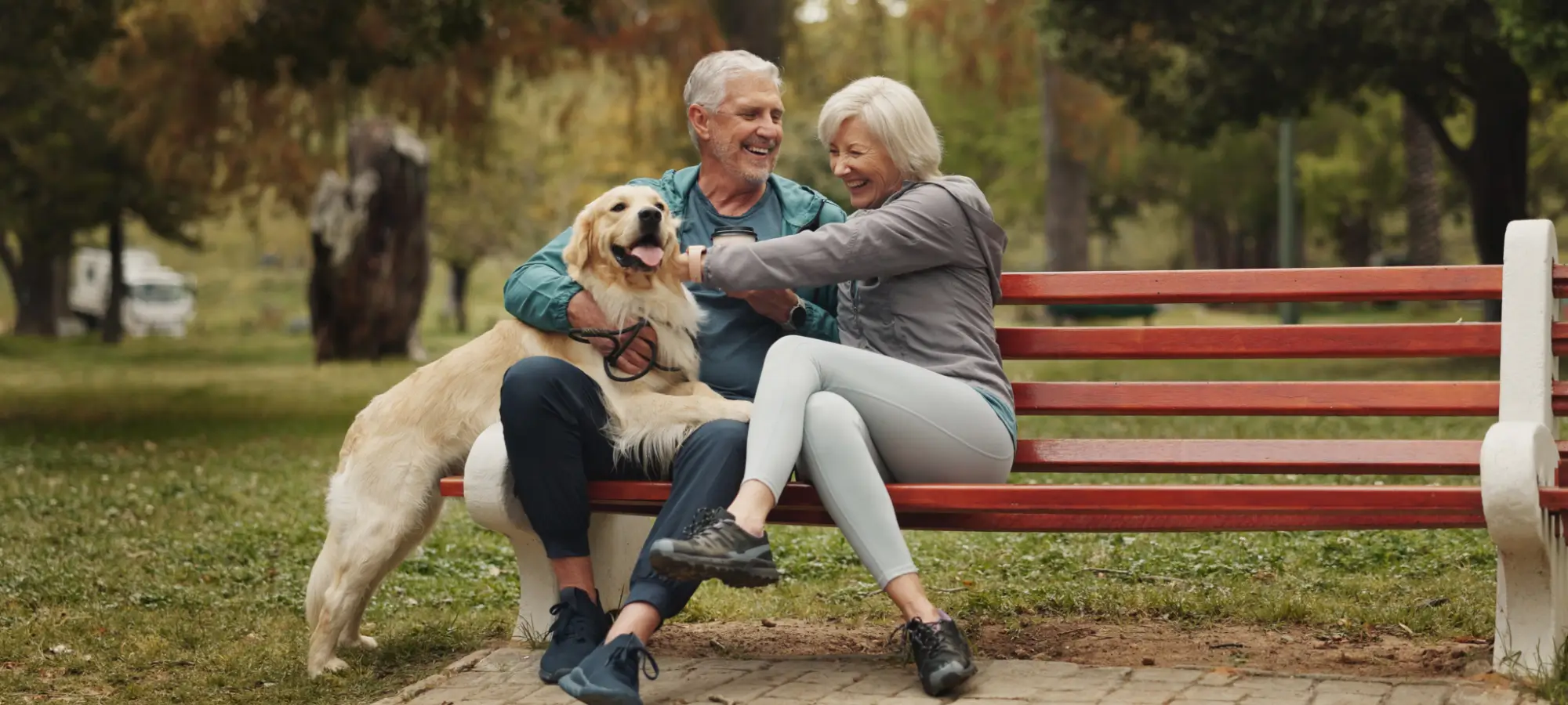 Older couple sitting on bench with their dog