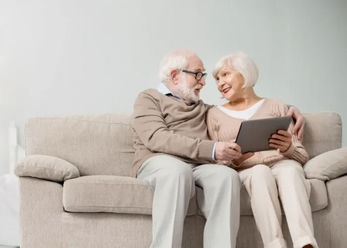Older couple sitting on couch looking at laptop