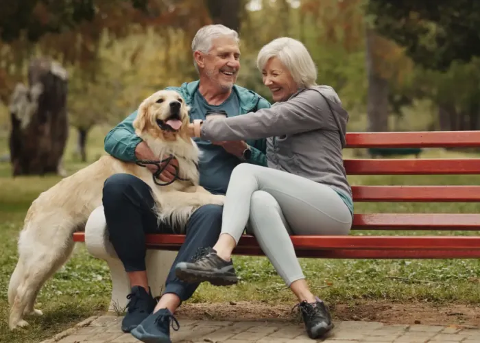 Older couple sitting on bench with their dog